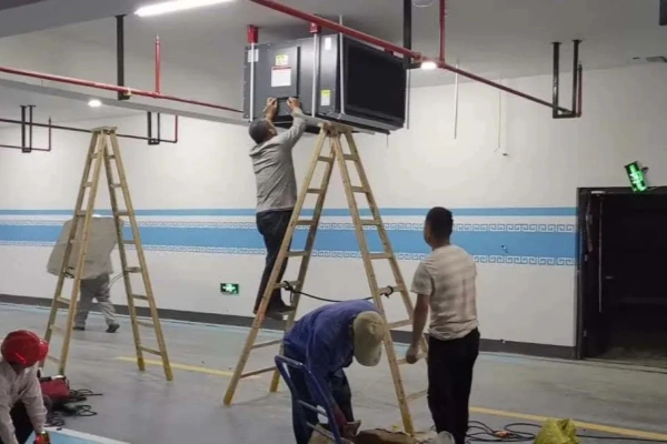 Installation crew on ladders working to install a large dehumidifier unit on the ceiling