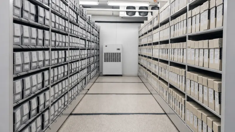Industrial dehumidifier installed in an archive records storage room with document shelving
