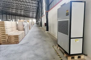 A large industrial dehumidifier unit operates in a warehouse with pallets of products